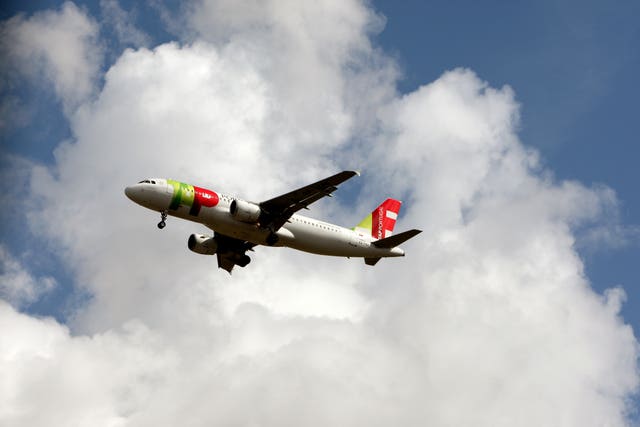 Plane with red tips on the wings against a white cloud, blue sky visible around the edges