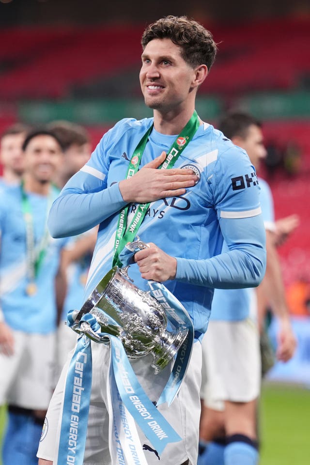 John Stones presses his hand to the Manchester City badge on his shirt as he celebrates with the Carabao Cup trophy last season