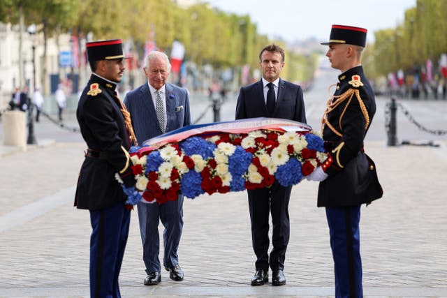 The King and president stand in front of the Tomb of the Unknown Soldier during a ceremonial welcome at the Arc de Triomphe