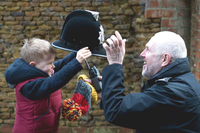 A police officer swaps hats with a child while the crowd waits (Aaron Chown/PA)