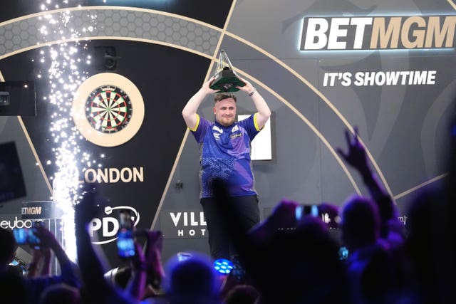 Luke Littler lifts the trophy as he celebrates victory