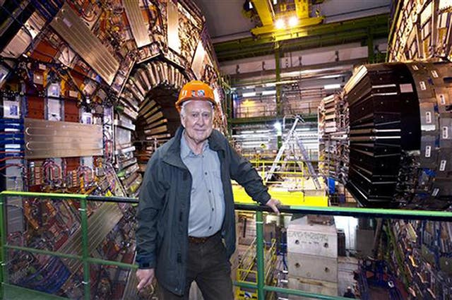 Professor Peter Higgs standing in front of the Large Hadron Collider
