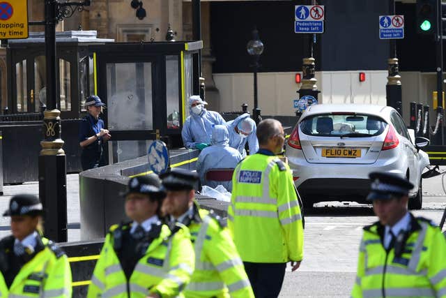 Forensic officers by the car that crashed into security barriers outside the Houses of Parliament