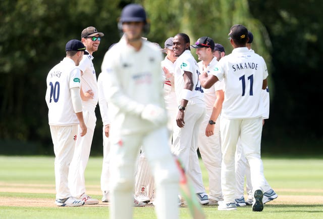 Jofra Archer, centre, looks back at departing batsman Tom Price after taking his first wicket