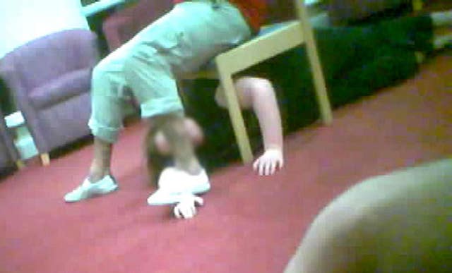 A care worker at Winterbourne View restraining a patient under a chair