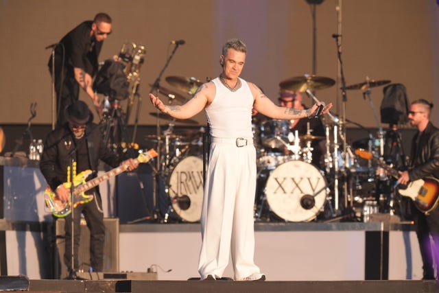Robbie Williams dressed in all white with his arms out stretched on stage at BST Hyde Park in London