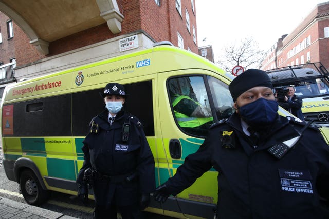 Police officers and security guards clear a pathway for the ambulance