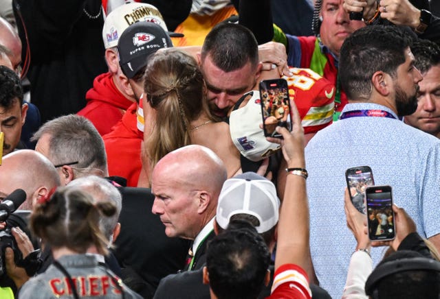 Taylor Swift and Travis Kelce hugging in a crowd