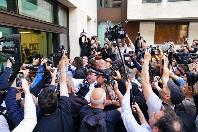 Photographers surround Russell Brand as he arrives at court