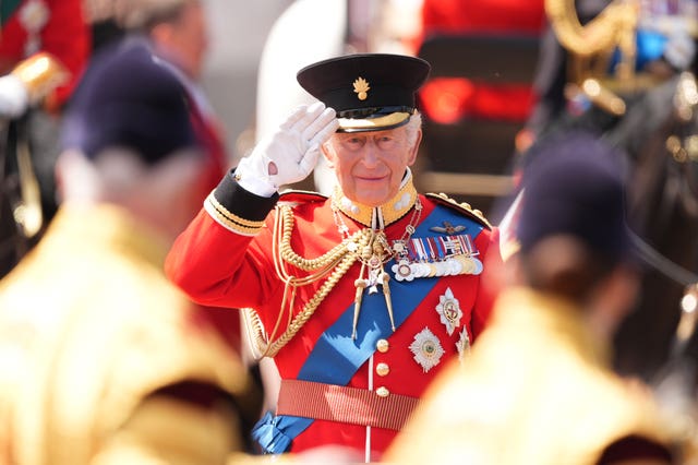 The King takes the salute during the march past in front of Buckingham Palace after the Trooping the Colour