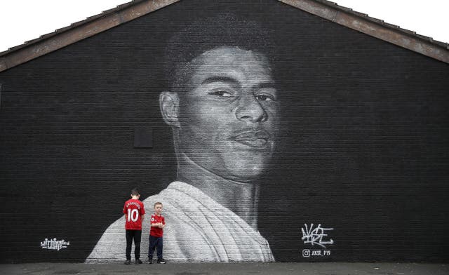 Manchester United fans pose in front of a mural of striker Marcus Rashford