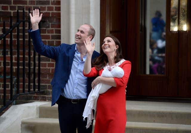 The delighted couple acknowledge the cheers of royal fans as they emerge from the hopsital with the prince (Kirsty O’Connor/PA)