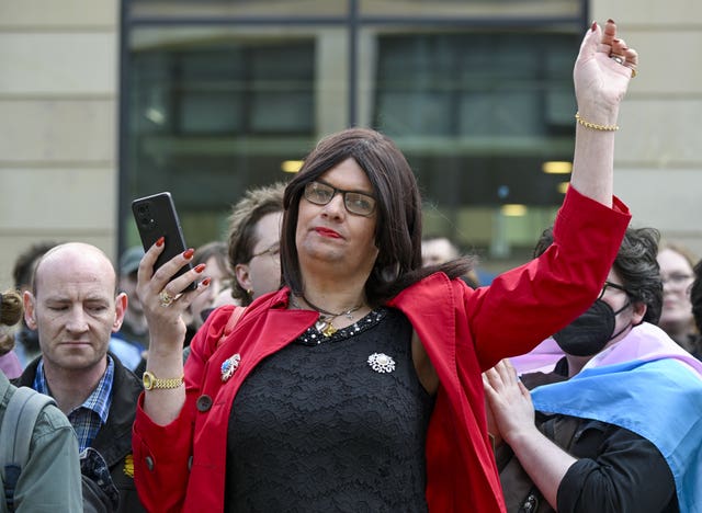 Trans rights protestor dressed in a red coat and black top