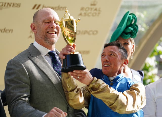 Frankie Dettori celebrates after being presented with a trophy by Mike Tindall and Zara Tindall after winning the Queen’s Vase on Gregory