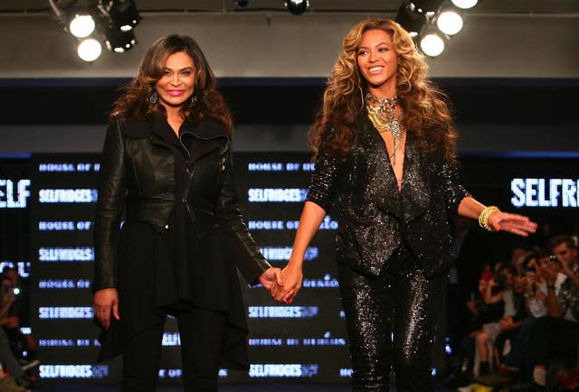 Beyonce Knowles holding hands with her mother Tina Knowles and smiling on a cat walk