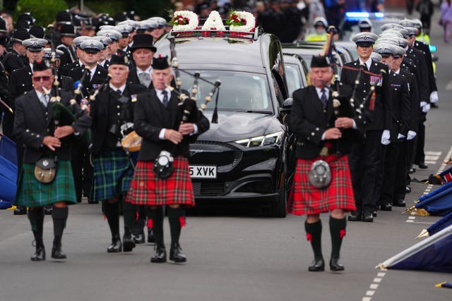 Bagpipers lead the funeral cortege through the streets