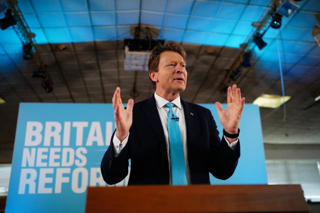 Richard Tice speaks at a lectern in front of a light-blue sign: