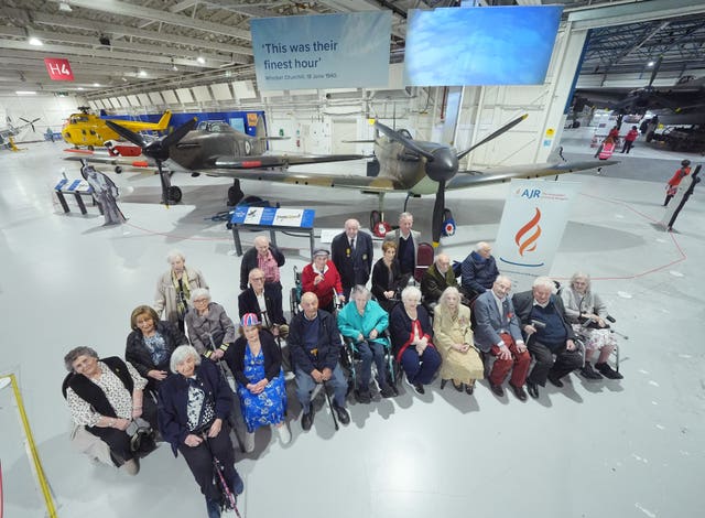 Holocaust survivors, refugees and descendants pose for a group photograph in front of an RAF spitfire