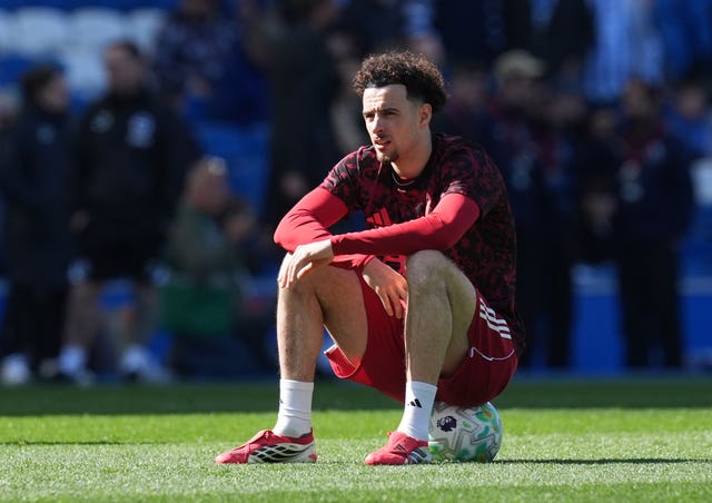 Liverpool midfielder Curtis Jones sits on a ball during the warm-up
