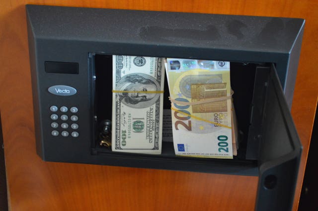 An open safe with bundles of euros and dollars