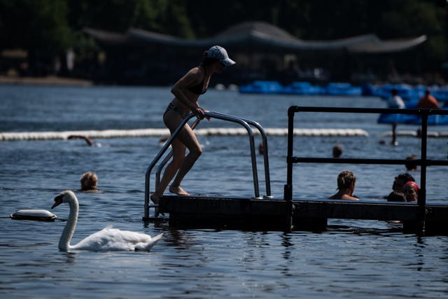 A person enters the water in the Serpentine, London during recent warm weather 