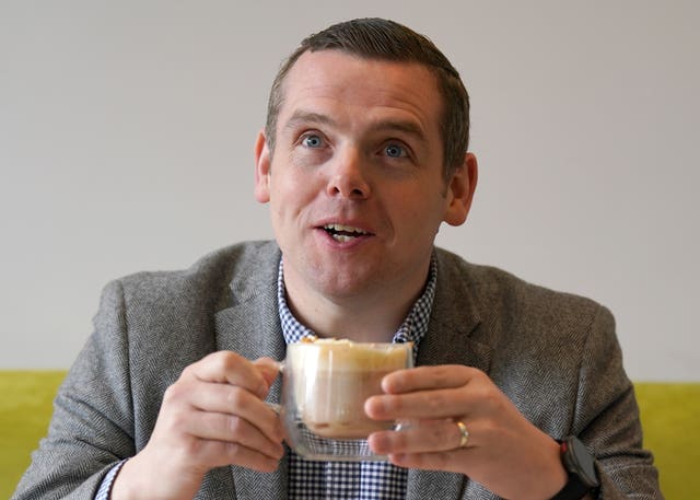 Douglas Ross drinking from a mug