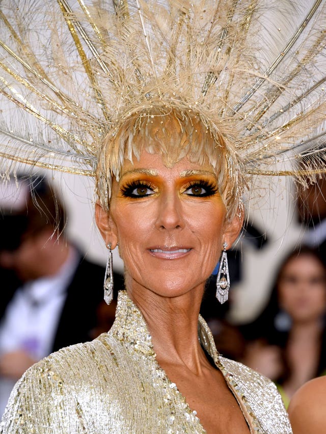 Singer Celine Dion in gold feathered headdress and large earrings