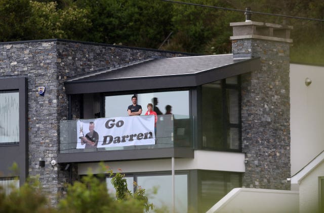 Spectators watch from a balcony with a banner of support for Clarke