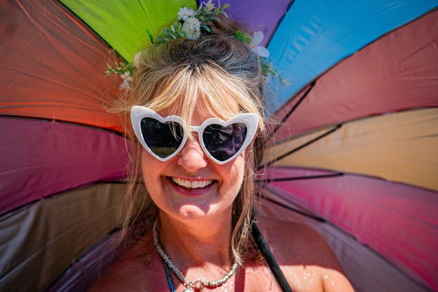 A festivalgoer wears sunglasses and carries a colourful brolly