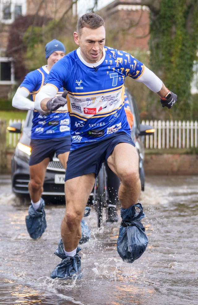 Kevin Sinfield sporting bin bags to cover his footwear as he runs through flood water in Cattal on day seven of his latest fundraising challenge