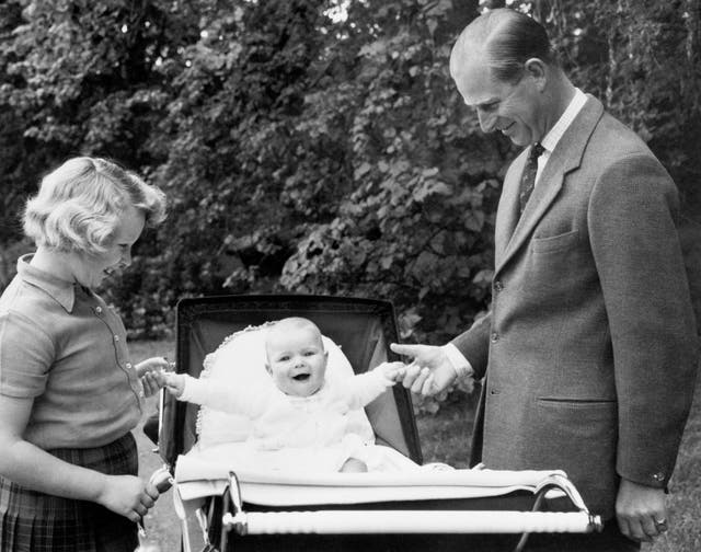 With one hand for his father, the Duke of Edinburgh, and the other for big sister Princess Anne, laughing Prince Andrew sits up in his pram in the grounds of Balmoral (PA)