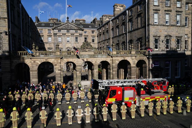 Firefighters lined up along a road in tribute as a fire engine passes by