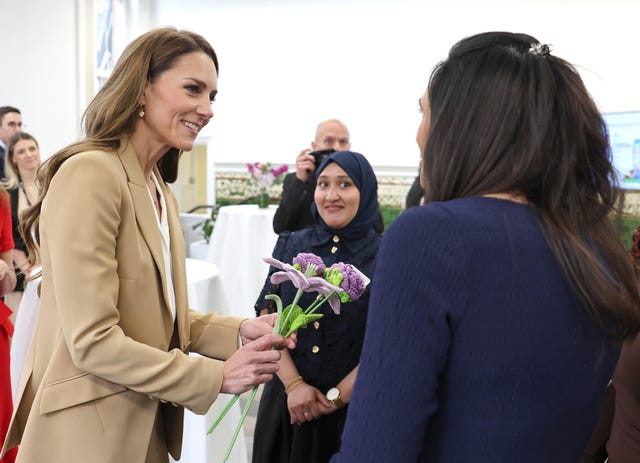Kate holds flowers after being presented with them during the visit