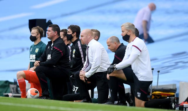 Burnley manager Sean Dyche and his staff take a knee before the Premier League match at the Etihad Stadium