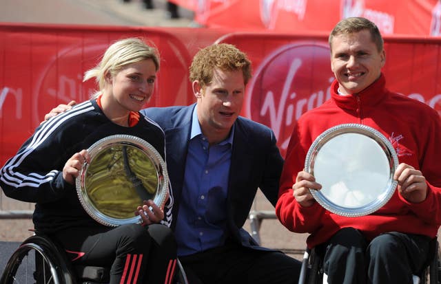 Prince Harry poses with Great Britain's Shelly Woods and David Weir after their victories in the wheelchair races in 2012