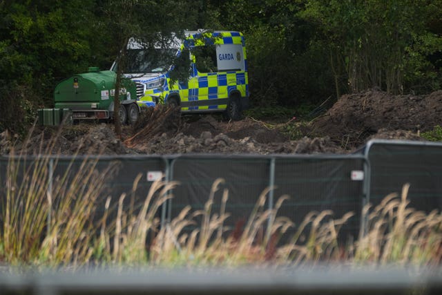 View of a Garda van on a field, behind hoarding