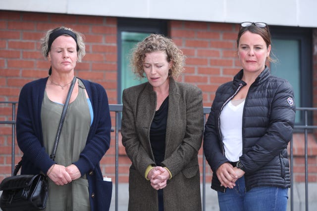 Fiona Donohoe, with her head bowed and hands clasped together, flanked by her sisters