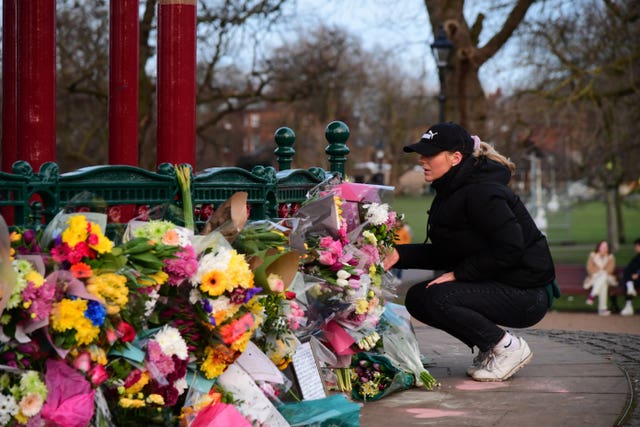 A woman leaves flowers at the bandstand on Clapham Common