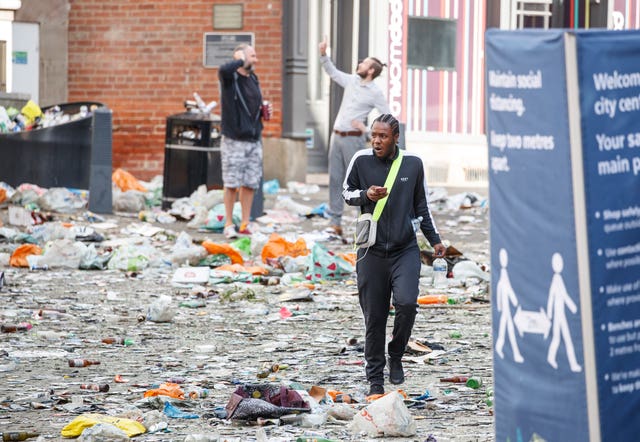 People walk past litter in the centre of Leeds after celebrations by fans whose football club won the Championship title and a return to the Premier League