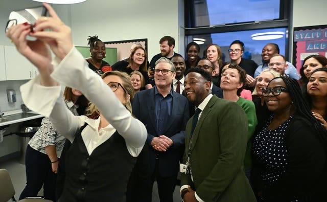 Sir Keir Starmer and Olivia Colman among a group posing for a selfie in a school