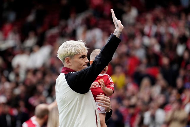Alejandro Garnacho, holding his young son, waves to the Manchester United fans after the win over Aston Villa