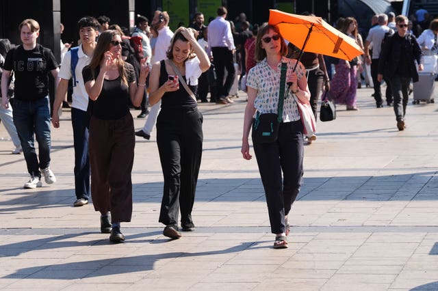 A woman using an umbrella for shade near Euston Station in central London