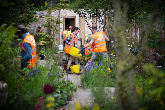 Workers makes final adjustments to a garden during a build day at the RHS Chelsea Flower Show