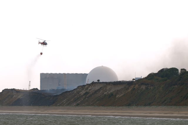 A helicopter flies water collected from the sea to drop on the wildfire at Dunwich Heath, near Leiston, close to the Sizewell B nuclear power station