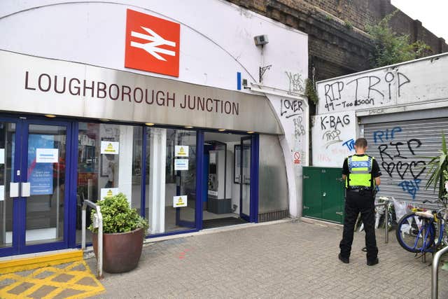 Flowers and three spray cans lay next to shutters at Loughborough Junction railway station (Dominic Lipinski/PA)