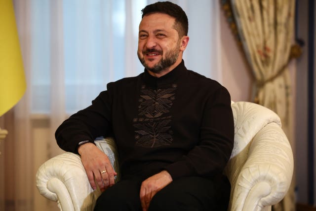 Volodymyr Zelensky smiling while sitting in armchair