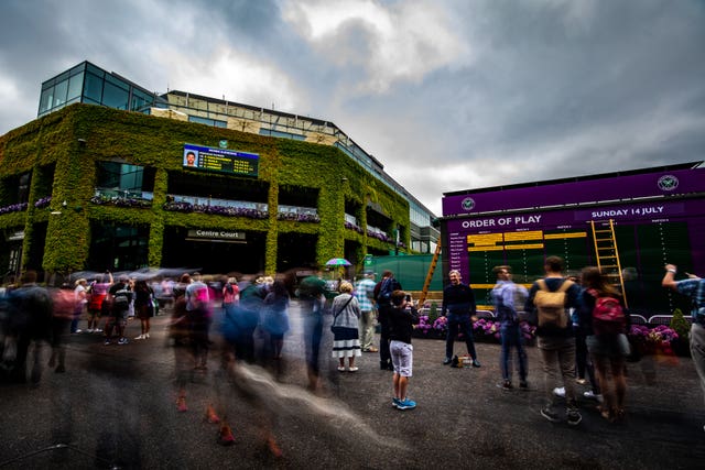 Spectators are led in on day thirteen of Wimbledon