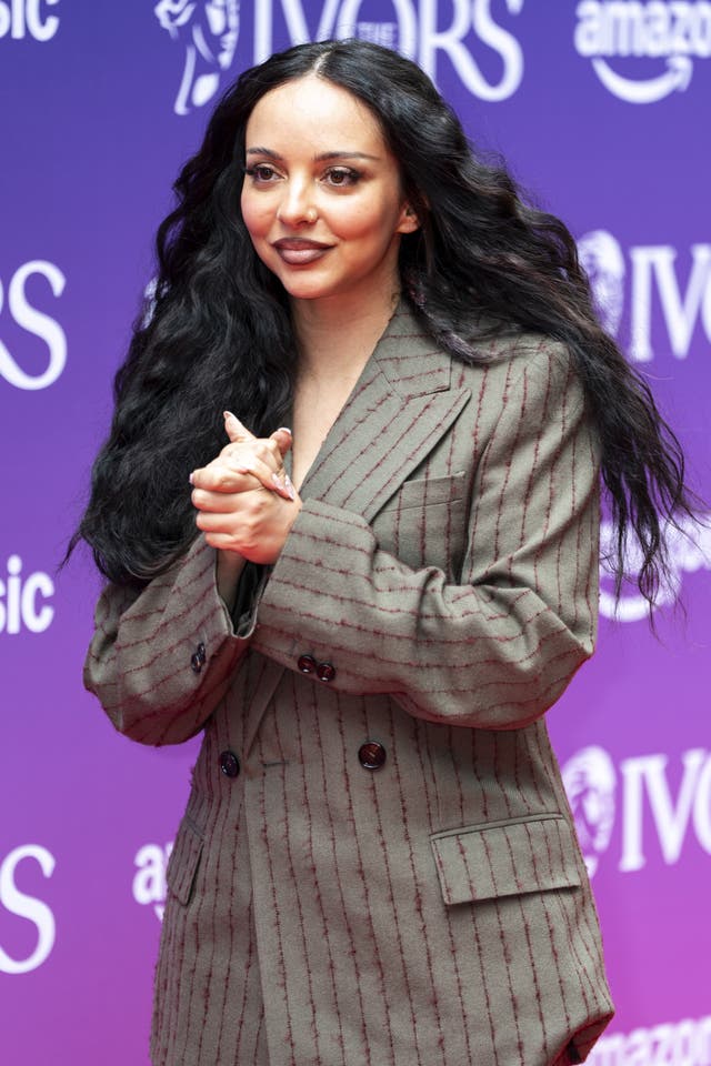 Jade Thirlwall holding her hands together wearing a pinstripe suit