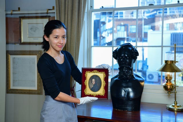 Louisa Price, curator at the Charles Dickens Museum in London, holding a portrait of the author by Margaret Gillies