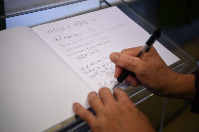 Visitors sign a book on the memorial shrine at Hackney Chinese Community Services